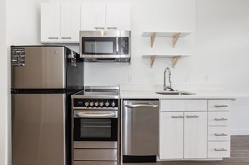A modern kitchen with a stainless steel refrigerator, oven, and microwave. at RiDE at RiNo Apartments, Colorado